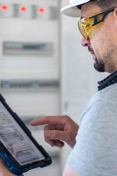 Man, an electrical technician working in a switchboard with fuses. Installation and connection of electrical equipment.
